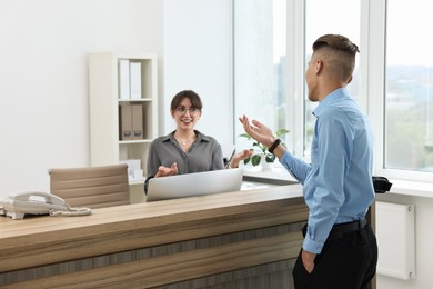 Photo of Professional receptionist working with client in office