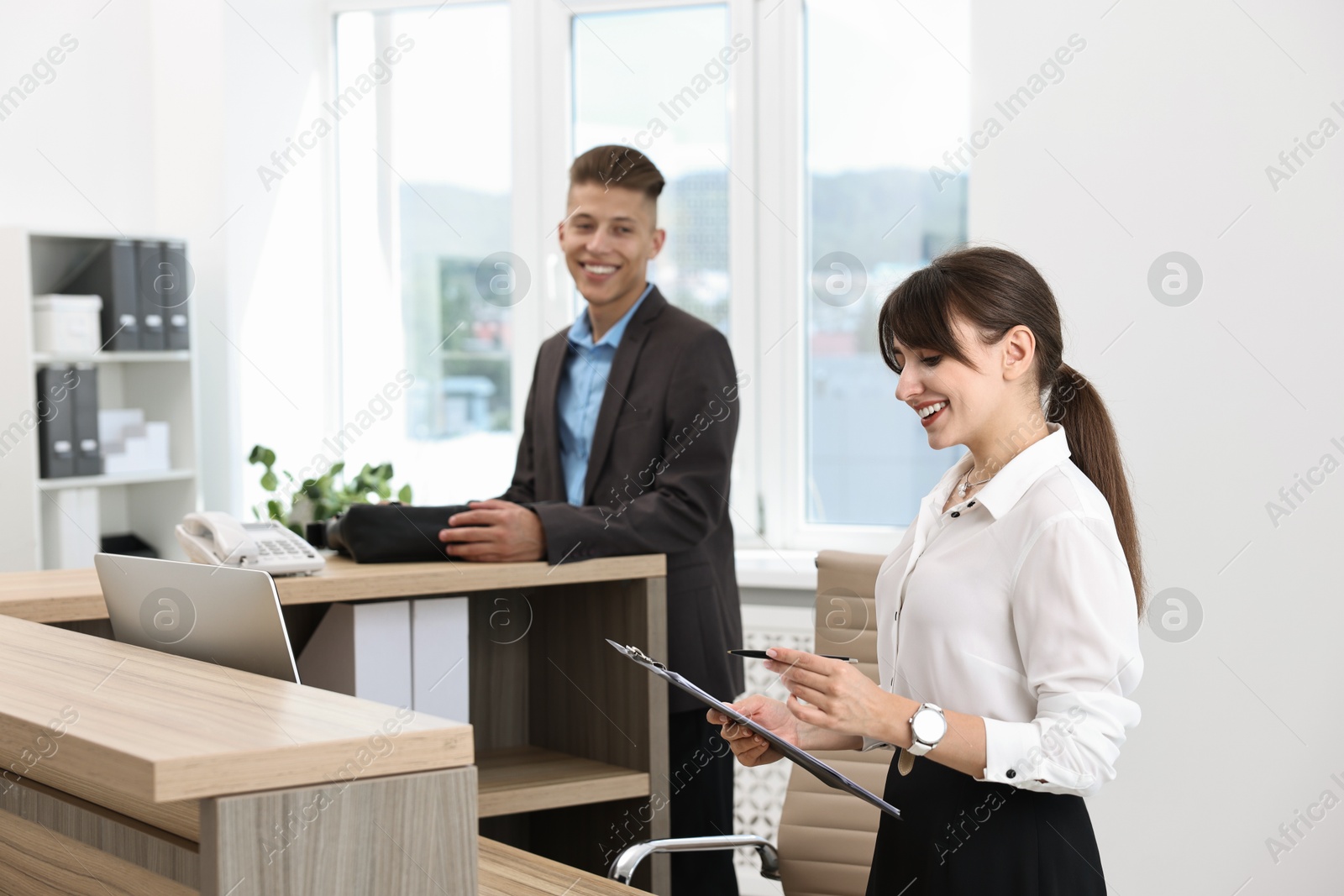 Photo of Professional receptionist working with client in office