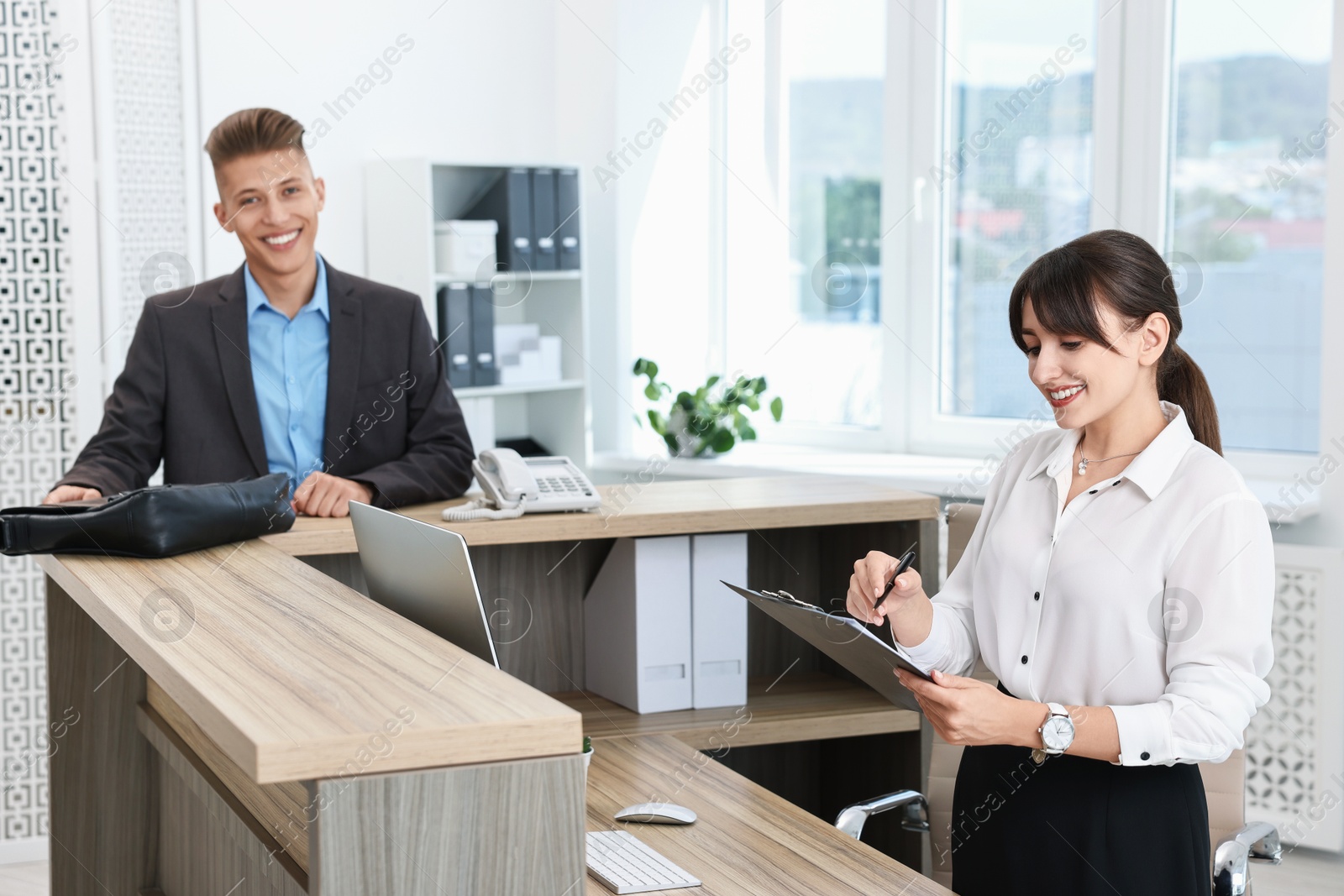 Photo of Professional receptionist working with client in office