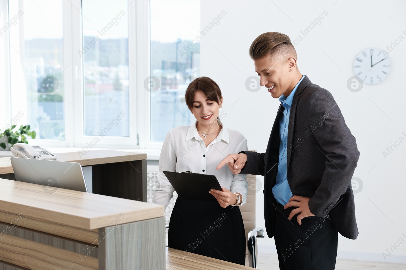 Photo of Professional receptionist working with client in office