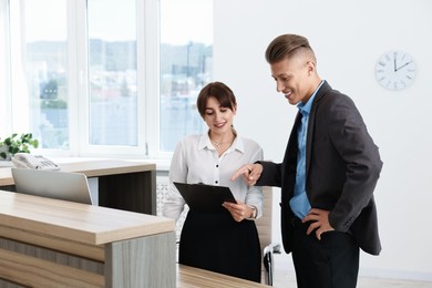 Photo of Professional receptionist working with client in office