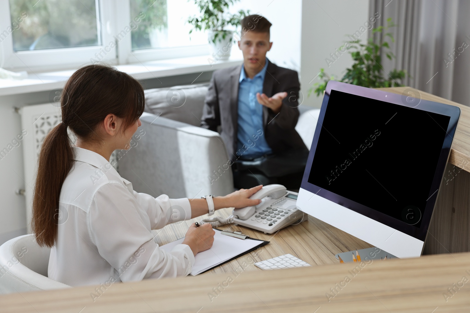 Photo of Professional receptionist working with client in office