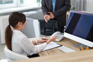 Photo of Professional receptionist working with client in office