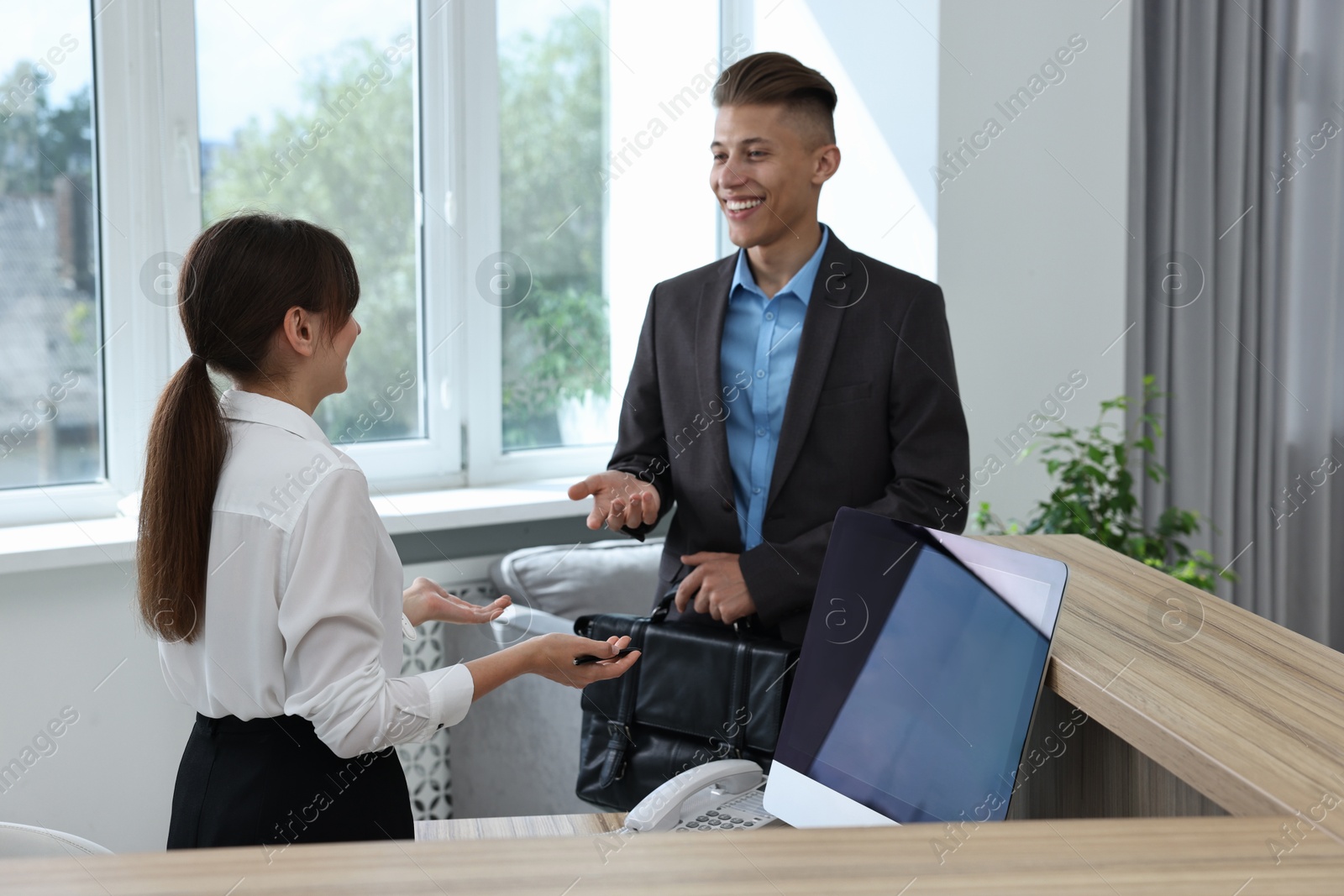 Photo of Professional receptionist working with client in office