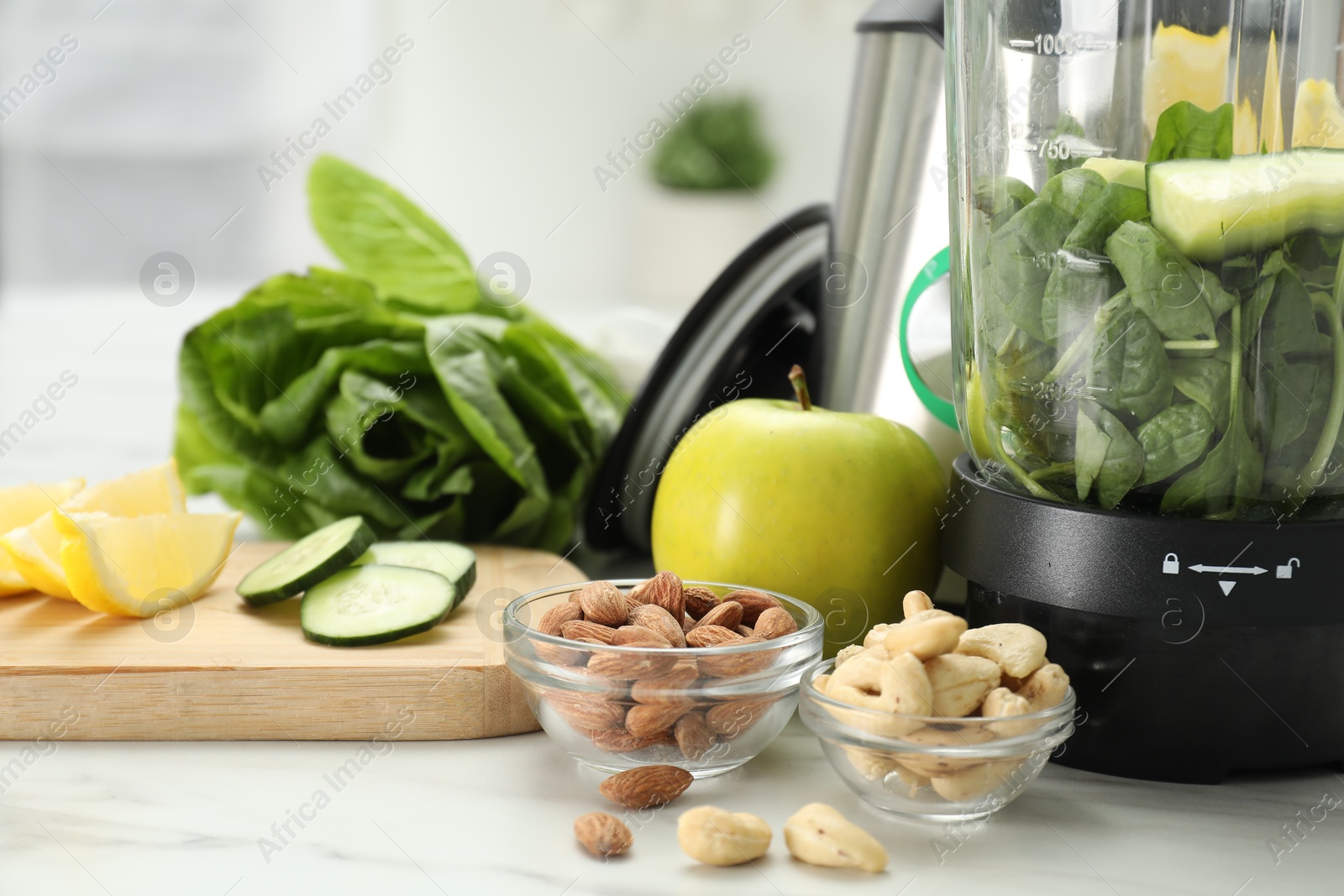 Photo of Modern blender with ingredients for smoothie on white marble table in kitchen, closeup