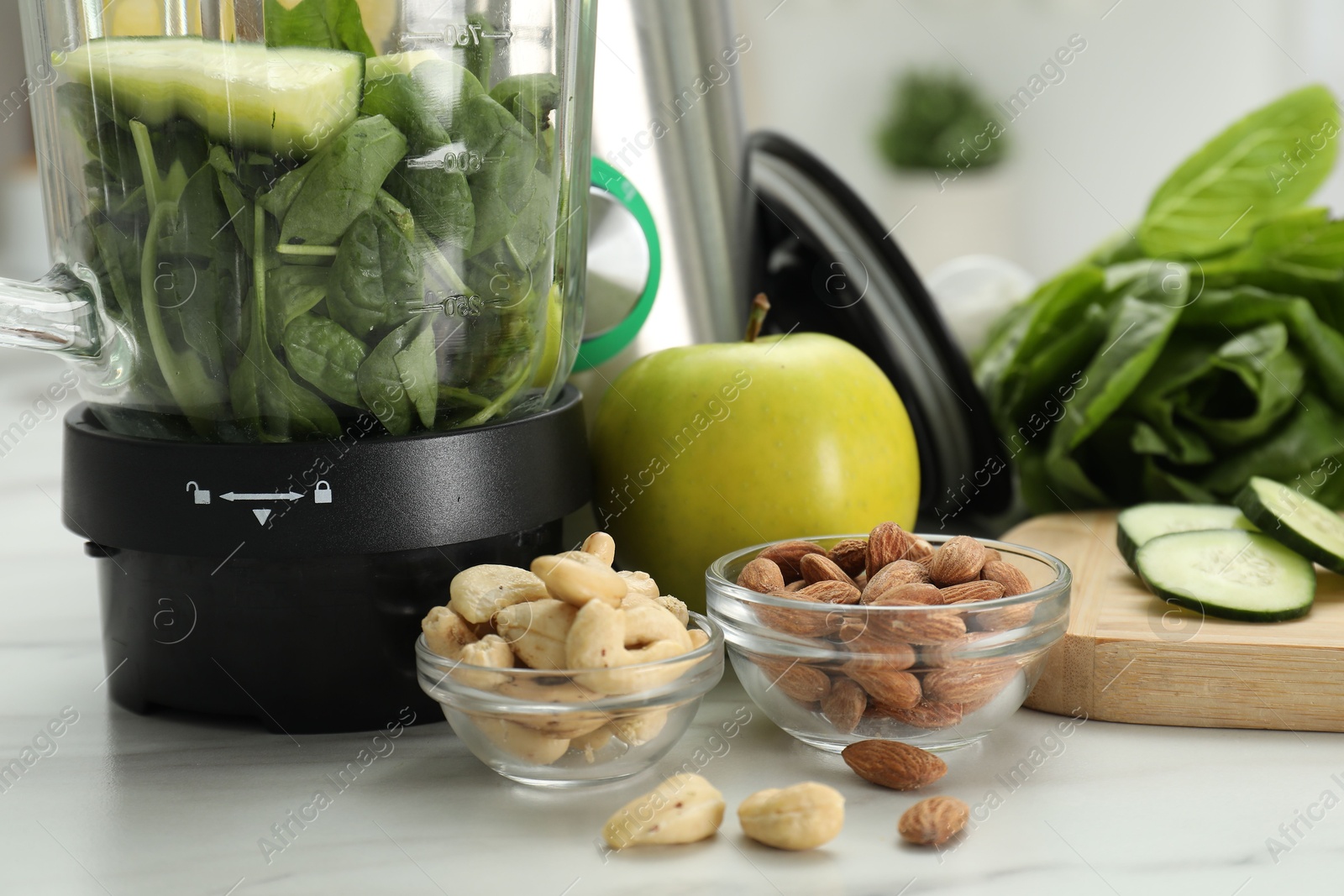 Photo of Modern blender with ingredients for smoothie on white marble table, closeup