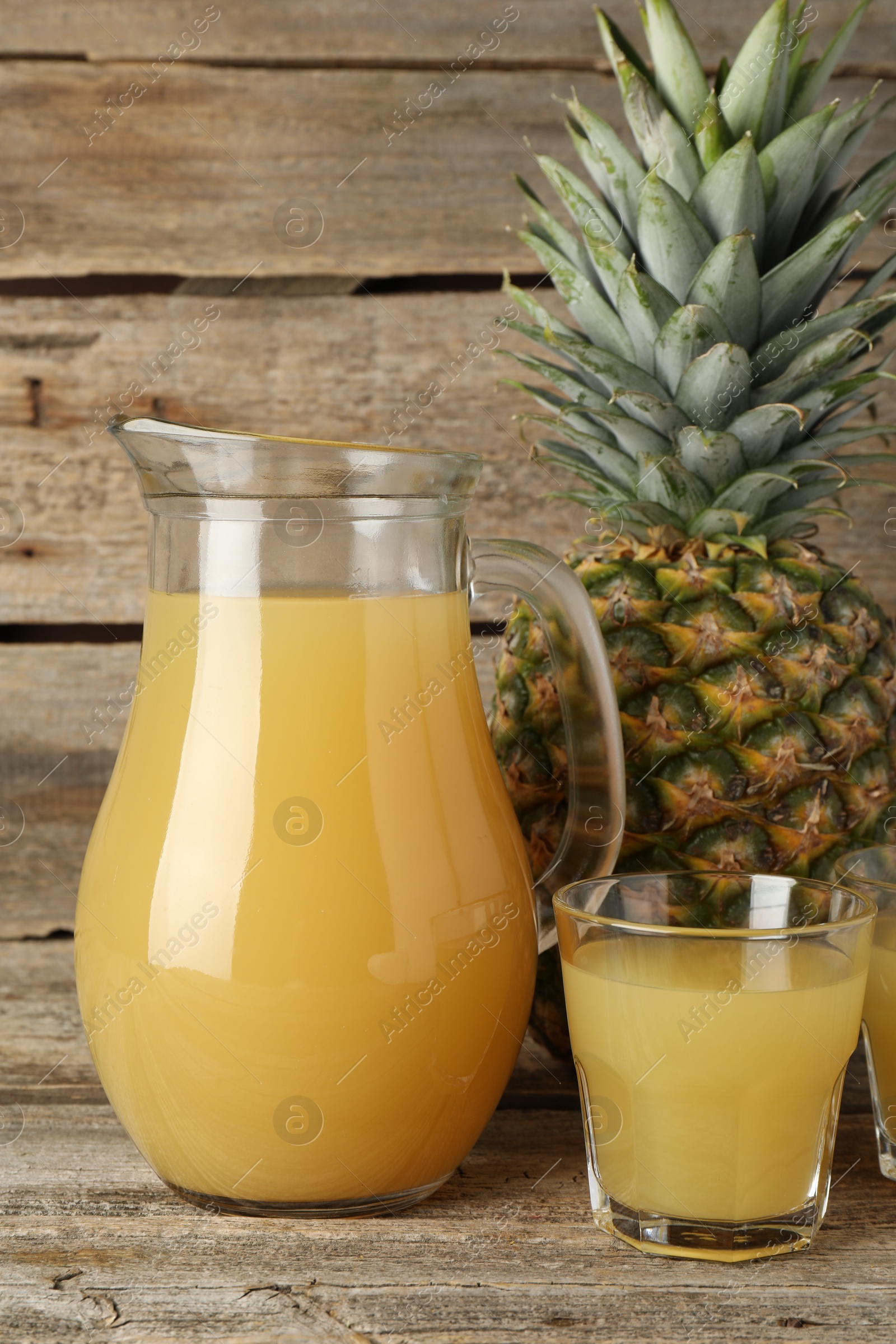 Photo of Tasty pineapple juice and fresh fruit on wooden table, closeup