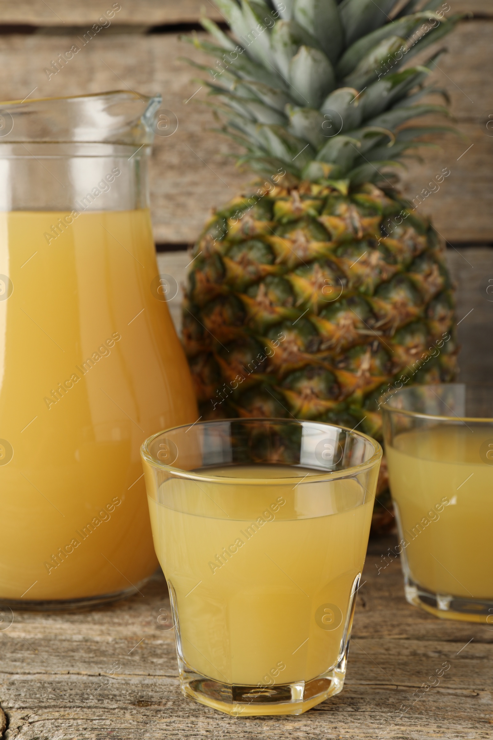 Photo of Tasty pineapple juice and fresh fruit on wooden table, closeup