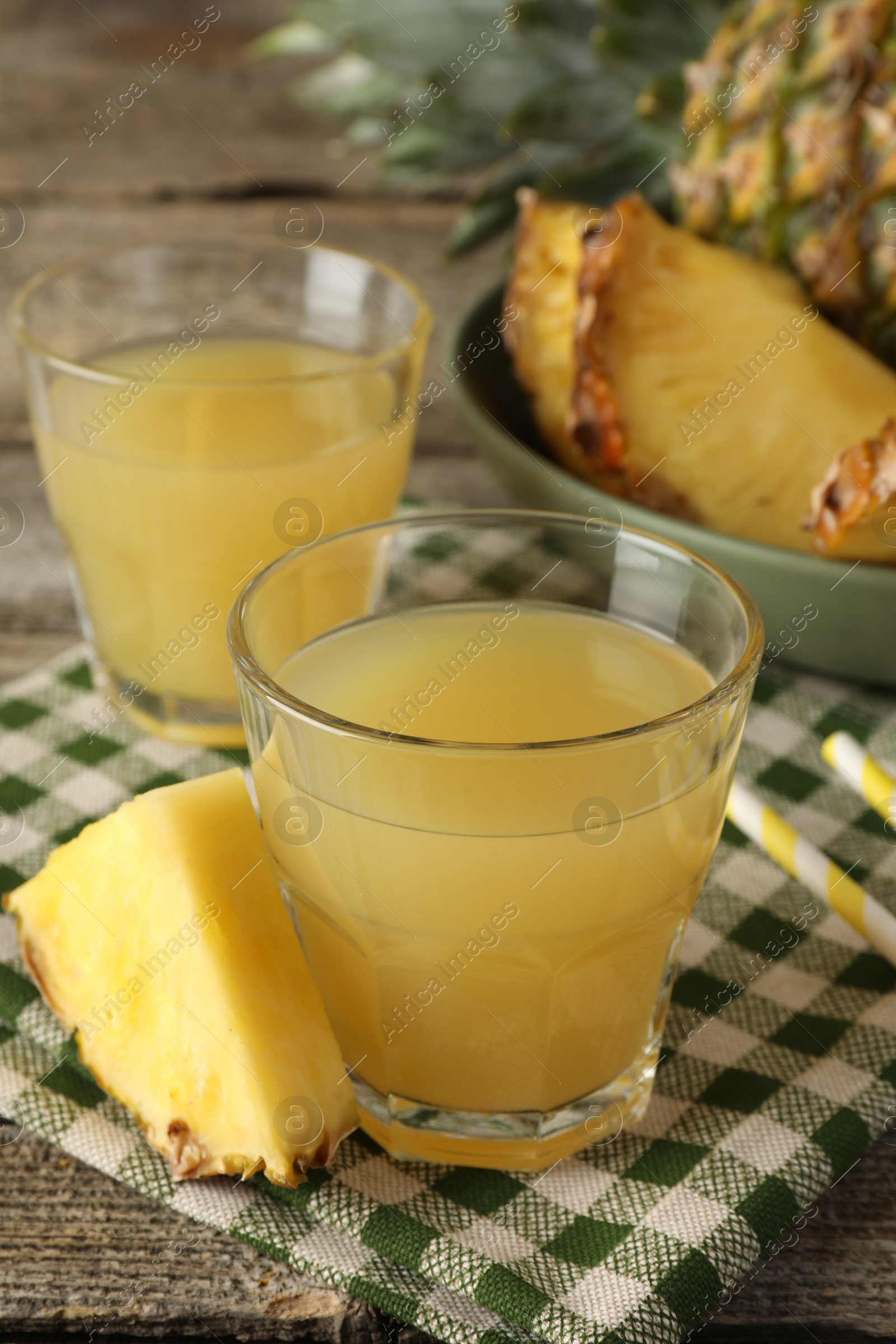 Photo of Tasty pineapple juice in glasses and slice of fresh fruit on wooden table, closeup