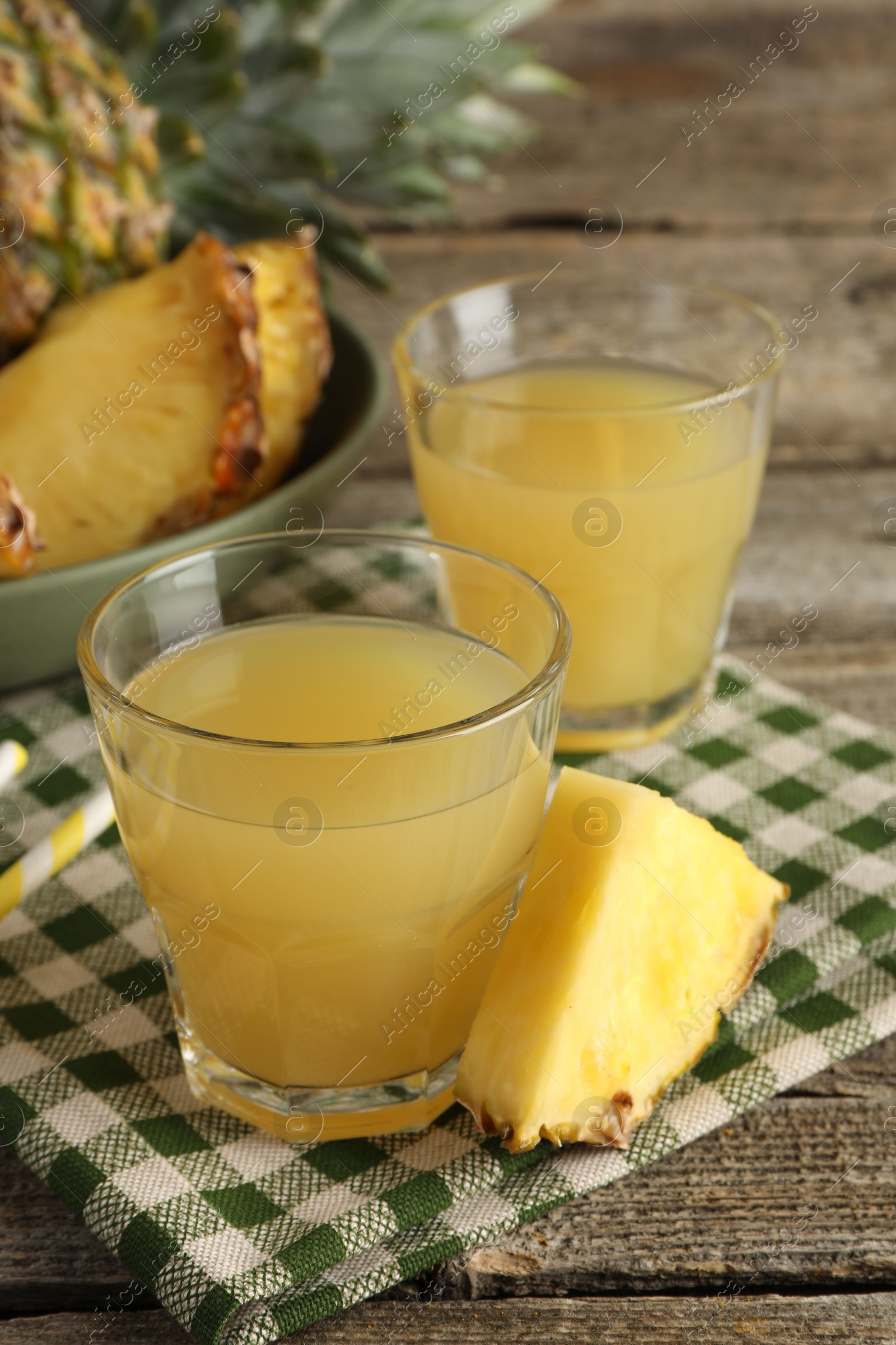 Photo of Tasty pineapple juice in glasses and slice of fresh fruit on wooden table, closeup