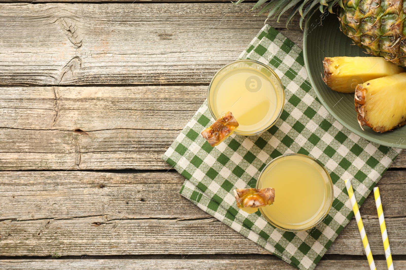 Photo of Tasty pineapple juice in glasses and fresh fruit on wooden table, flat lay. Space for text