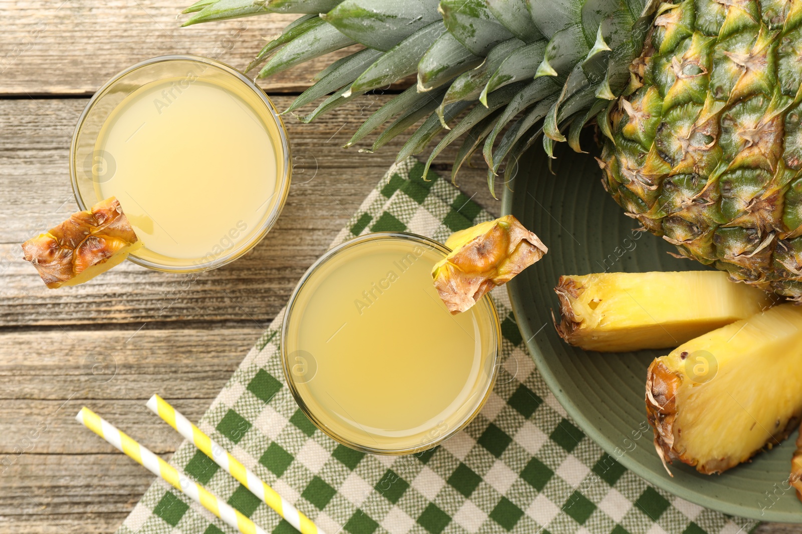 Photo of Tasty pineapple juice in glasses and fresh fruit on wooden table, flat lay