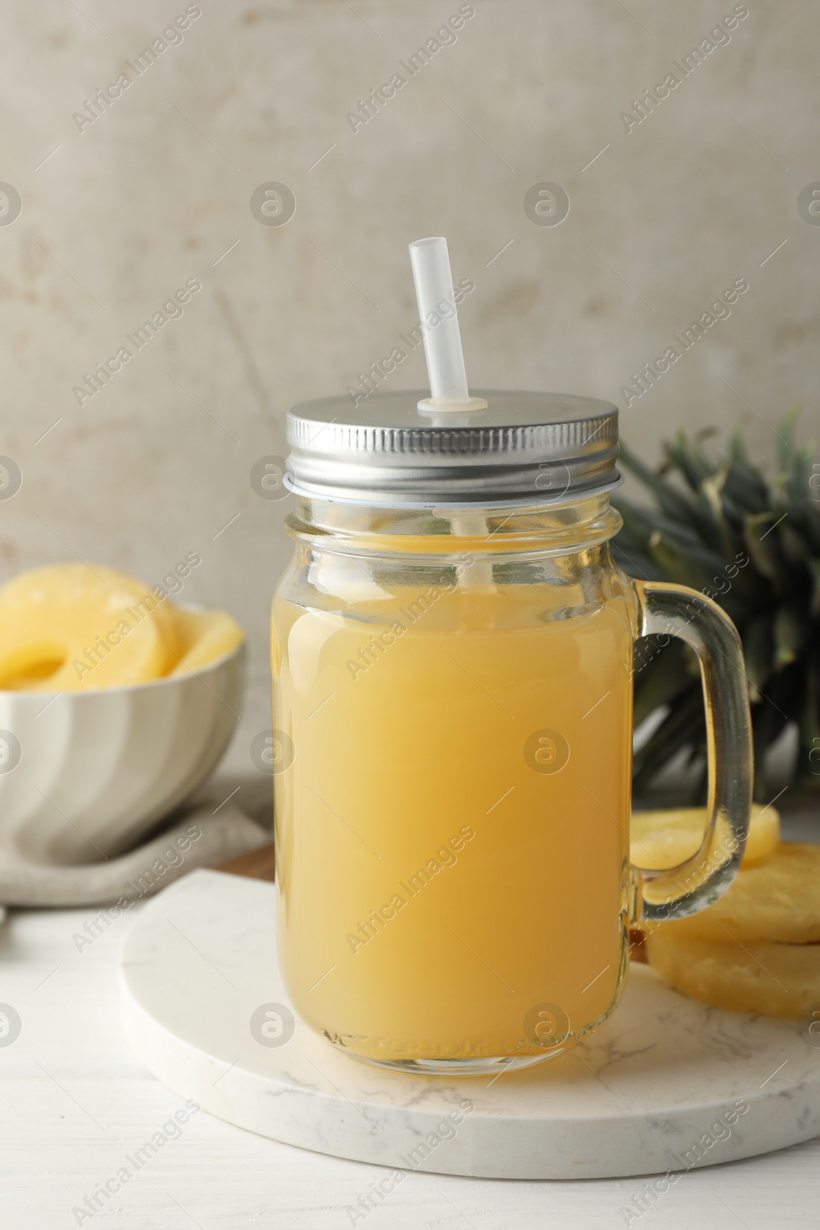 Photo of Tasty pineapple juice in mason jar and fresh fruits on white wooden table against grey background, closeup