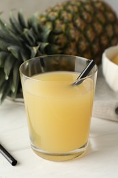 Photo of Tasty pineapple juice in glass and fresh fruit on white wooden table, closeup