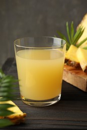 Photo of Tasty pineapple juice in glass on wooden table, closeup