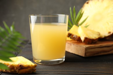 Photo of Tasty pineapple juice in glass on wooden table, closeup