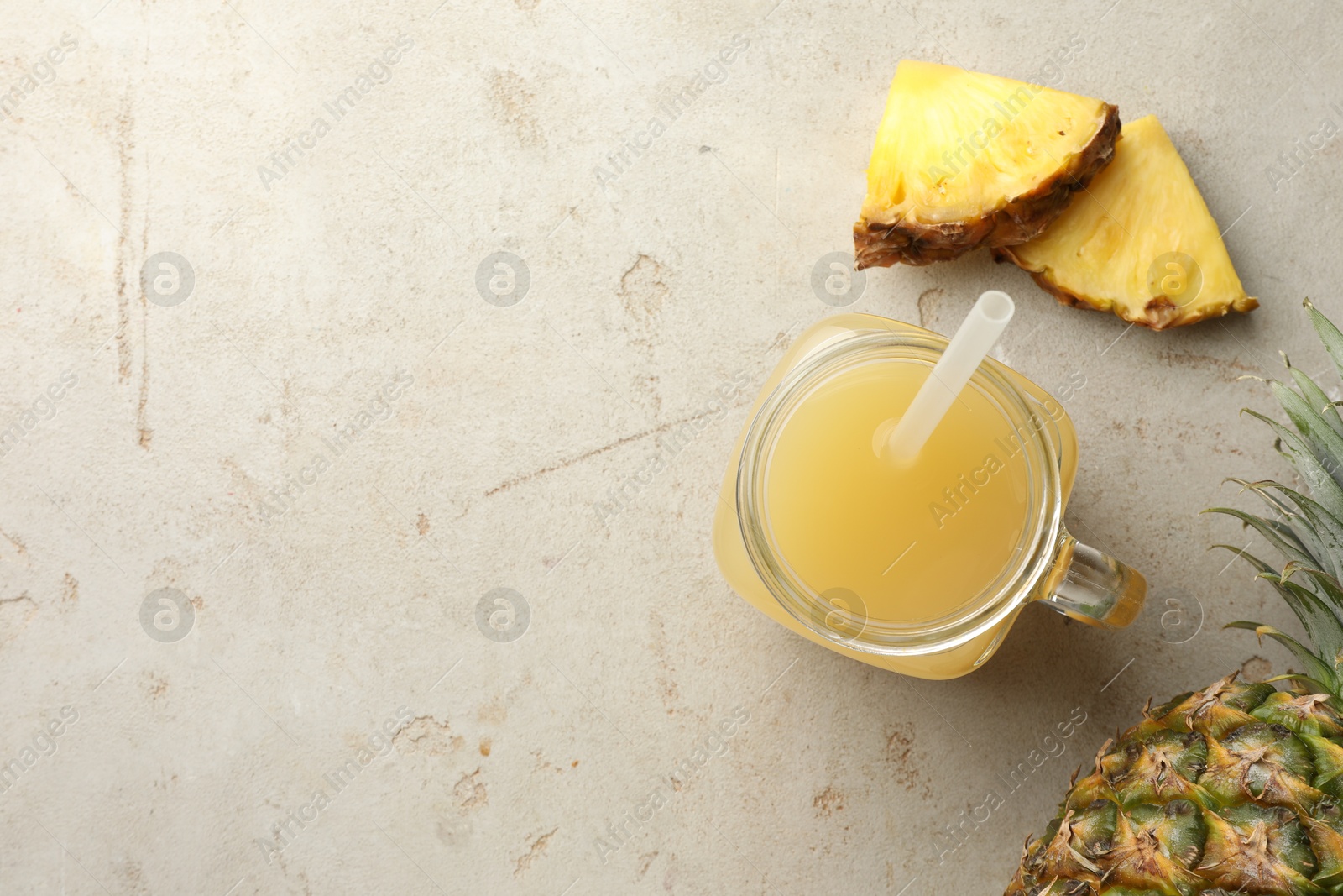 Photo of Tasty pineapple juice in mason jar and fresh fruits on grey textured table, flat lay. Space for text