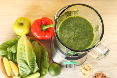 Modern blender with smoothie and ingredients on light wooden table, top view