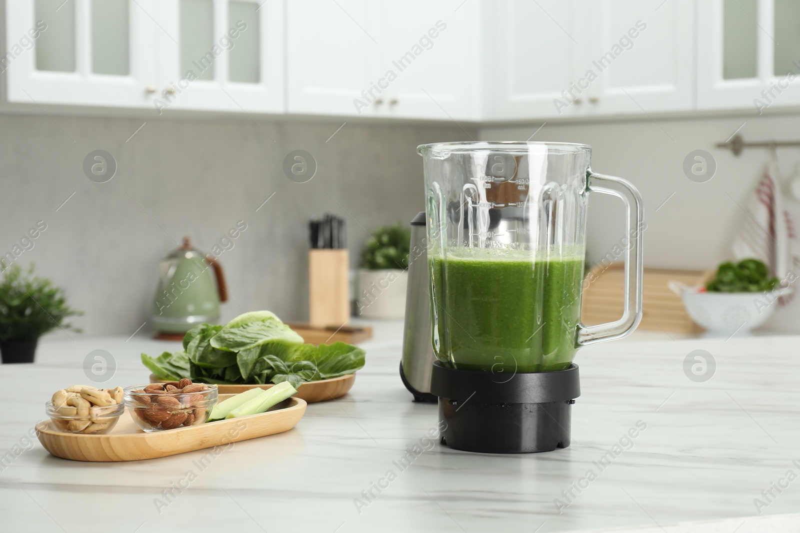 Photo of Modern blender with smoothie and ingredients on white marble table in kitchen