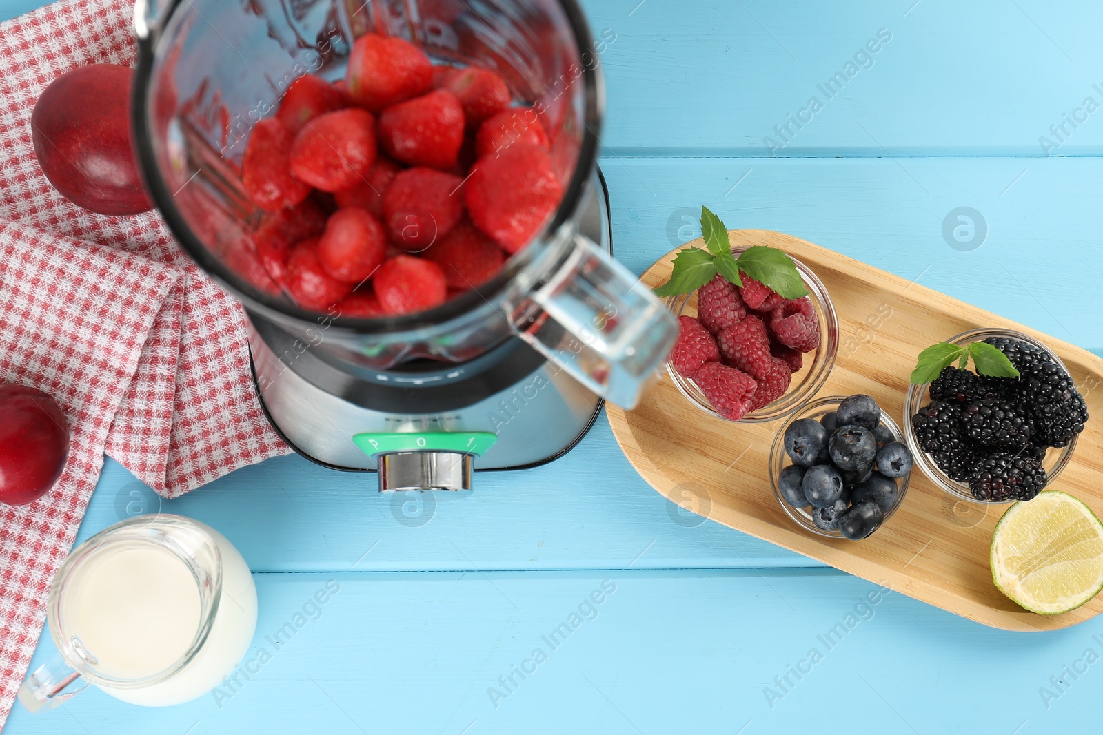 Photo of Blender and fresh ingredients on light blue wooden table, top view