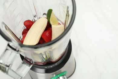 Photo of Blender with fresh ingredients on white table, closeup. Space for text