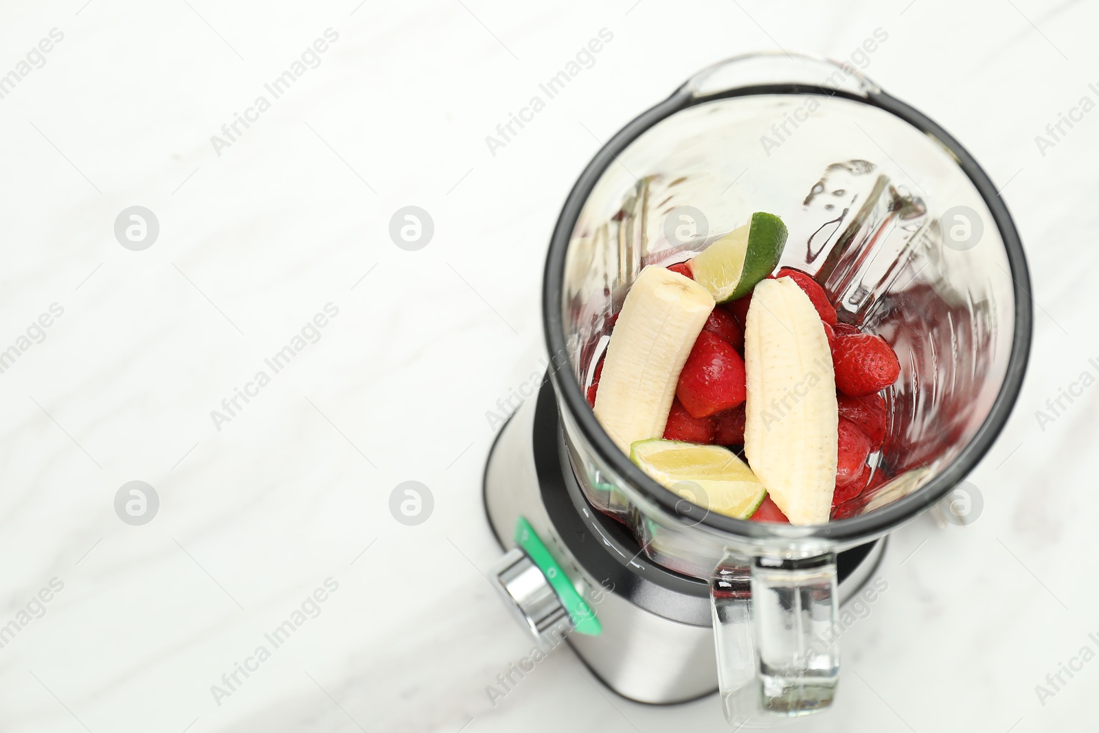 Photo of Blender and fresh ingredients on white marble table, above view. Space for text