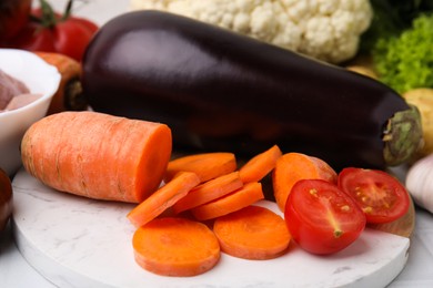 Photo of Cooking tasty stew. Cut carrot, tomato and eggplant on table, closeup