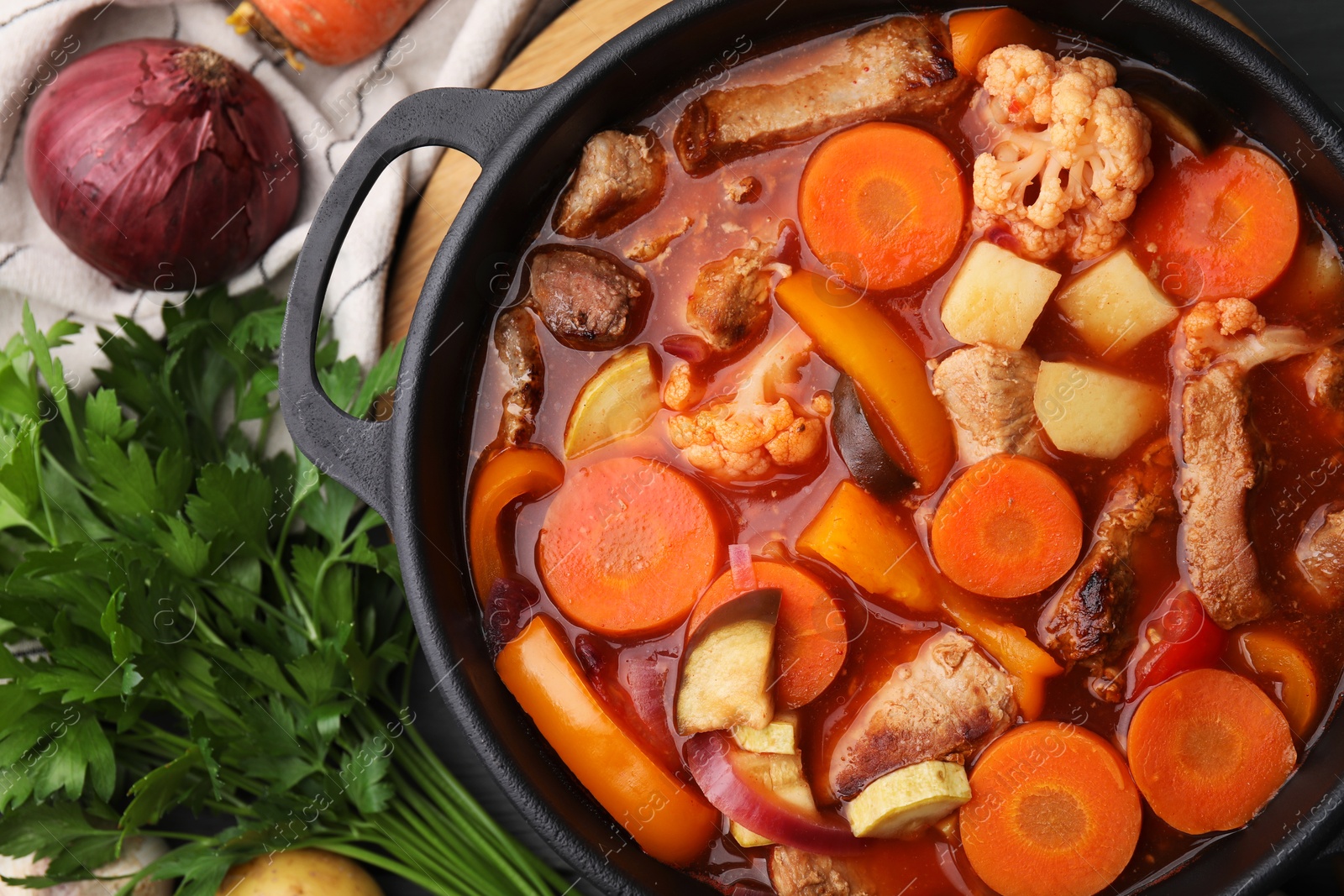 Photo of Tasty homemade stew with vegetables on grey wooden table, flat lay