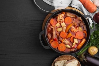 Photo of Tasty homemade stew with vegetables and bread on grey wooden table, flat lay. Space for text