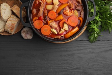 Photo of Tasty homemade stew with vegetables and bread on grey wooden table, flat lay. Space for text