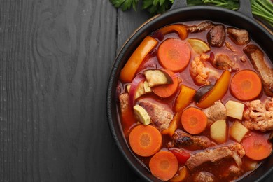 Photo of Tasty homemade stew with vegetables on grey wooden table, top view. Space for text