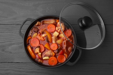 Photo of Tasty homemade stew with vegetables on grey wooden table, top view