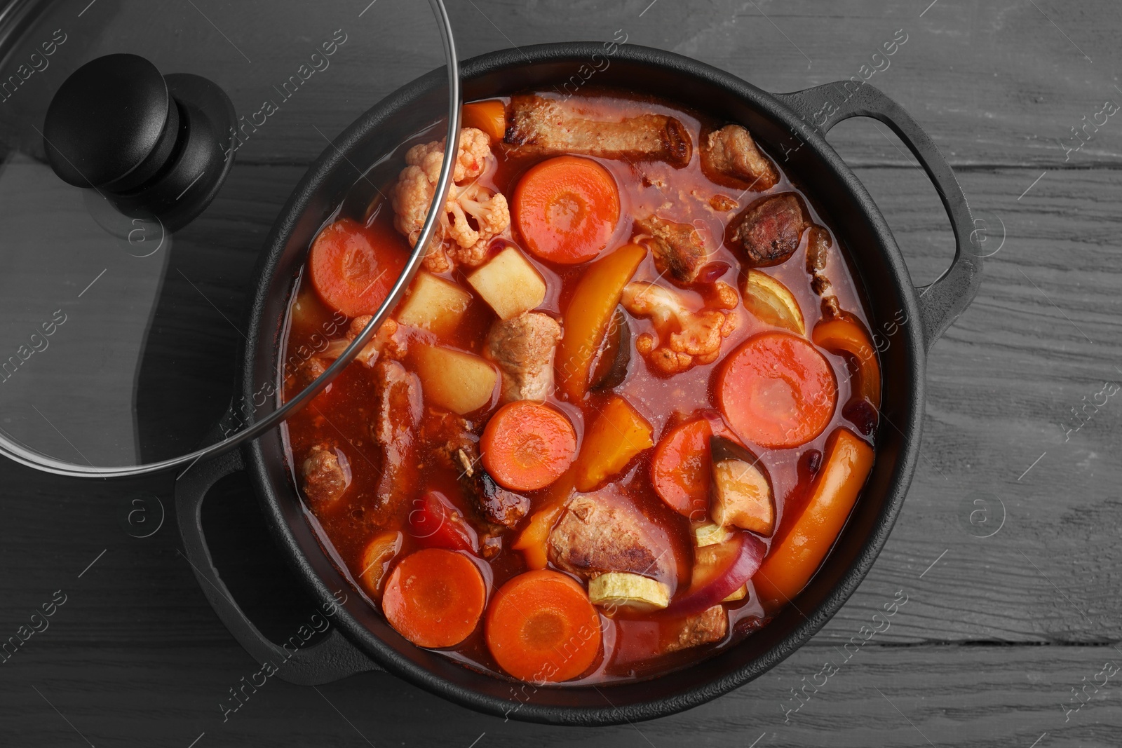 Photo of Tasty homemade stew with vegetables on grey wooden table, top view