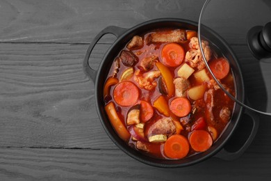 Tasty homemade stew with vegetables on grey wooden table, top view. Space for text