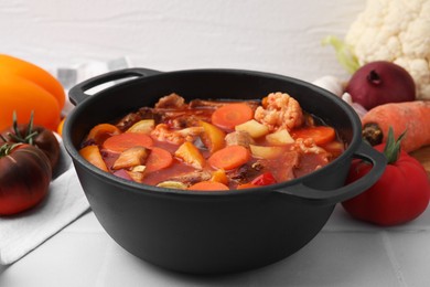 Photo of Tasty homemade stew with vegetables on white tiled table, closeup