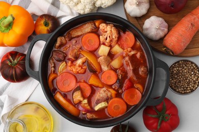 Photo of Tasty homemade stew with vegetables on white tiled table, flat lay