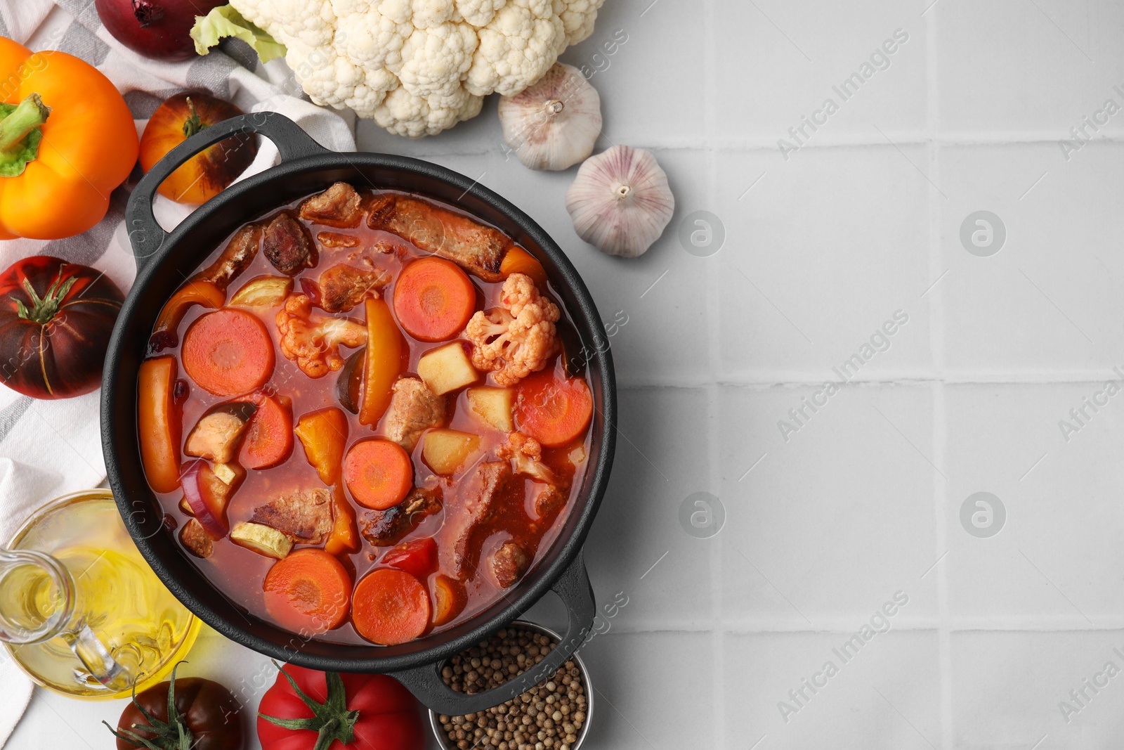 Photo of Tasty homemade stew with vegetables on white tiled table, flat lay. Space for text