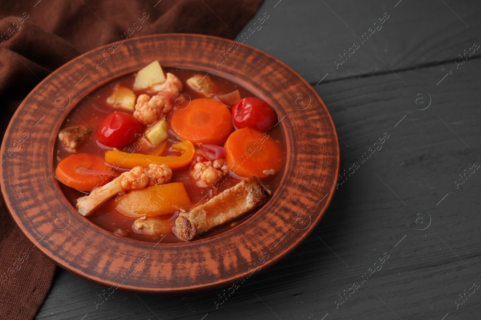 Photo of Tasty homemade stew with vegetables on grey wooden table, closeup. Space for text