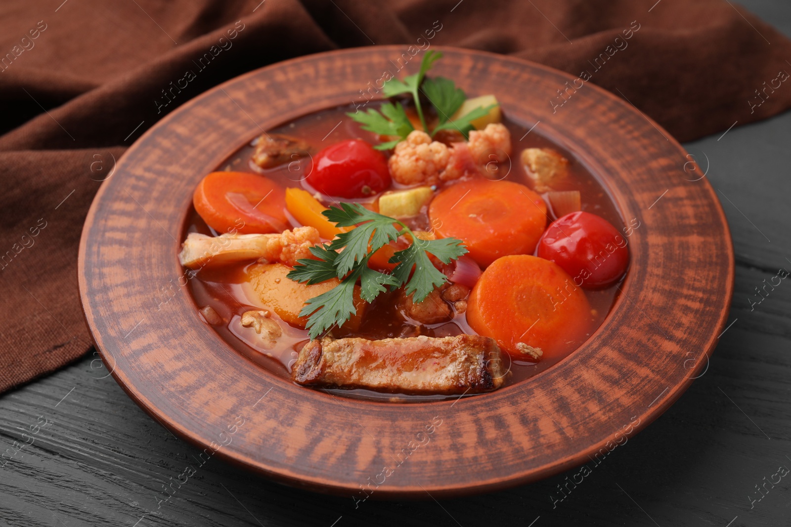 Photo of Tasty homemade stew with vegetables on grey wooden table, closeup