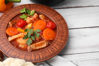 Tasty homemade stew with vegetables on white wooden table, closeup. Space for text