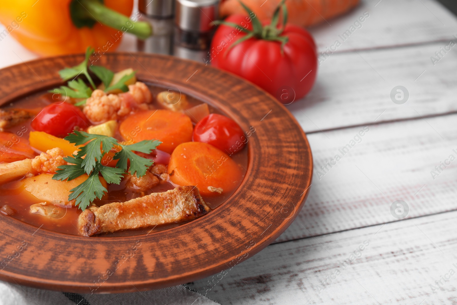 Photo of Tasty homemade stew with vegetables on white wooden table, closeup. Space for text