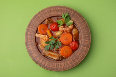 Tasty homemade stew with vegetables on light green table, top view