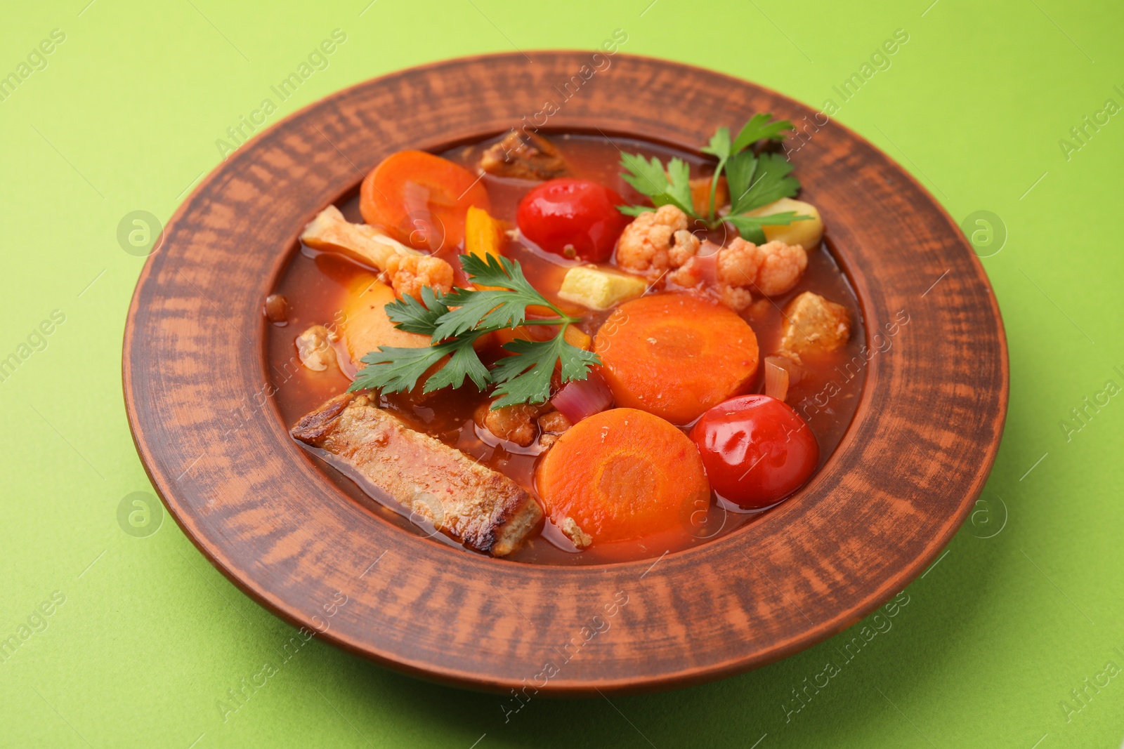 Photo of Tasty homemade stew with vegetables on light green table, closeup