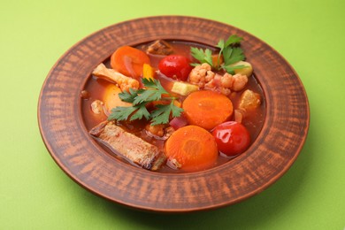 Tasty homemade stew with vegetables on light green table, closeup