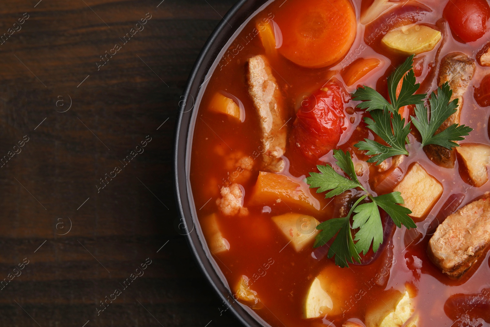 Photo of Tasty homemade stew with vegetables on wooden table, top view. Space for text