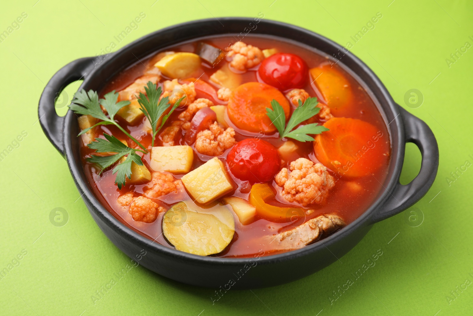 Photo of Tasty homemade stew with vegetables on light green table, closeup