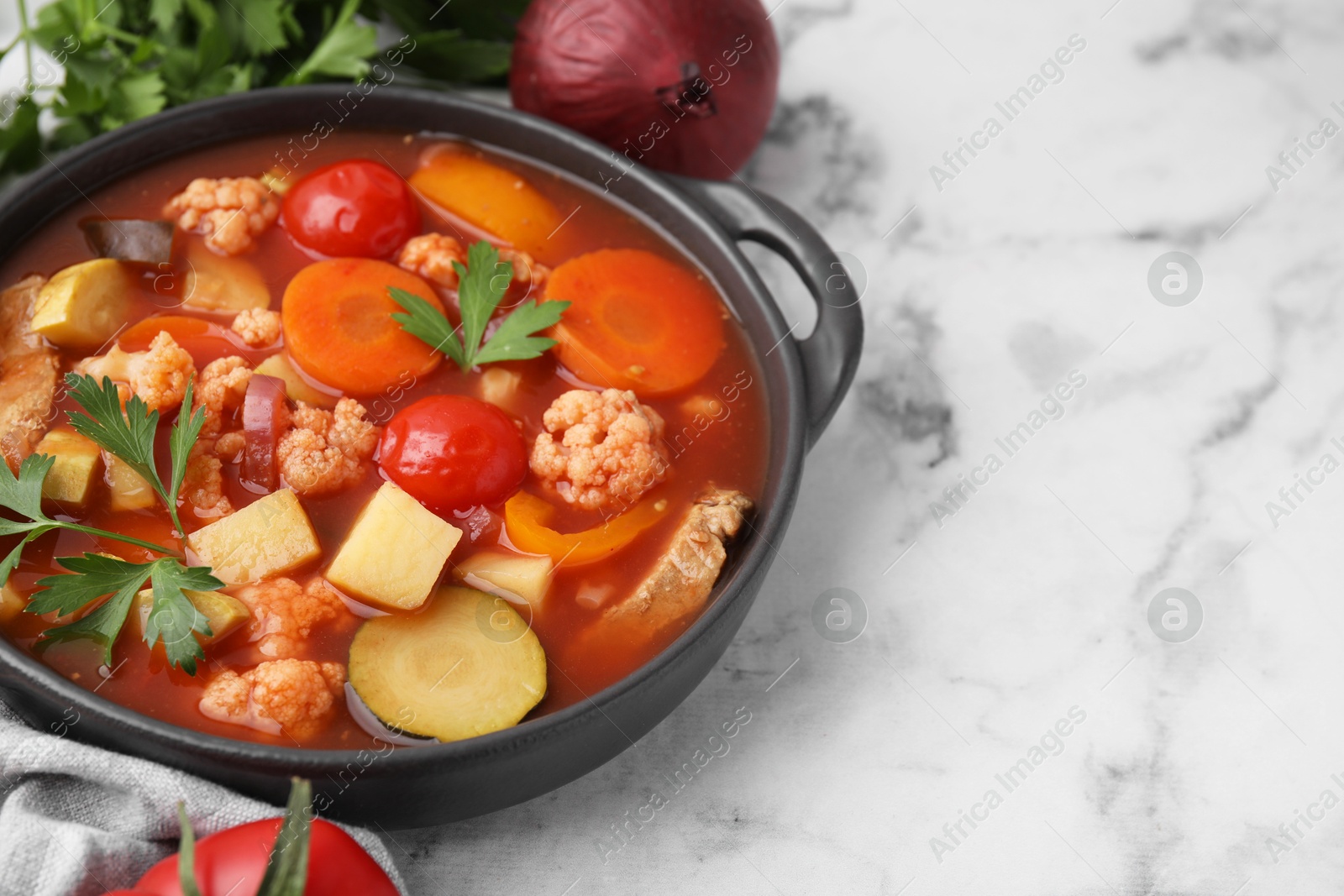 Photo of Tasty homemade stew with vegetables on white marble table, closeup. Space for text