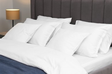 Photo of Many soft pillows on bed at home