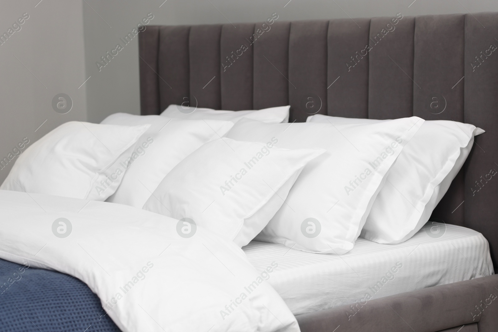 Photo of Many soft pillows on bed at home