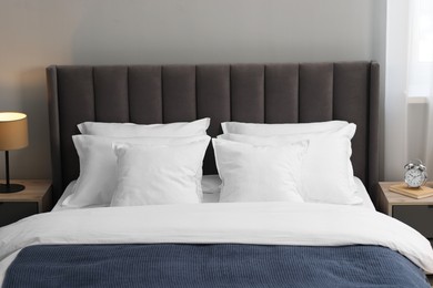 Many soft pillows on bed and bedside tables at home